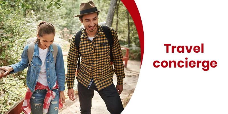 A man and woman stroll along a forest path in casual outdoor attire, backpacks in tow. To the right, the text Travel Concierge Services is prominently displayed against a striking white and red backdrop.